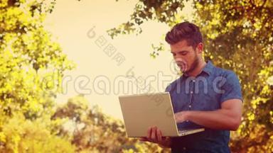 帅哥在公园里用笔记本电脑